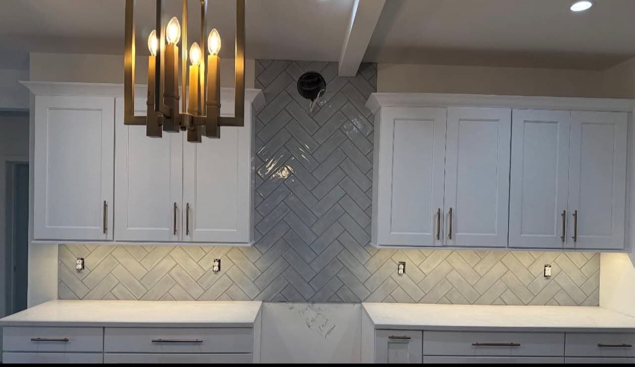 Herringbone ceramic tile kitchen backsplash with white cabinets installed by Costa Bathroom Remodel in Brandon, Florida