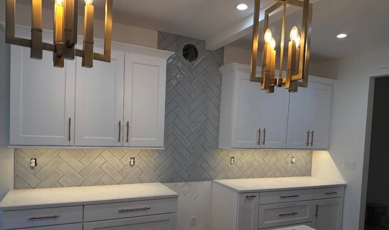 Herringbone cream tile kitchen backsplash with brass pendant lights installed by Costa Bathroom Remodel in Riverview, Florida